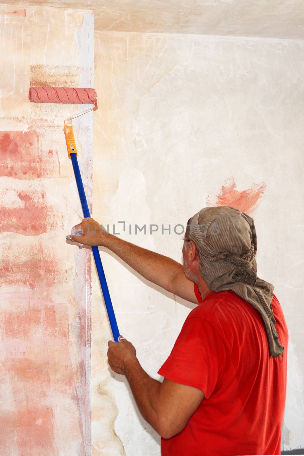 a man with a paint roller applies a primer to the wall.