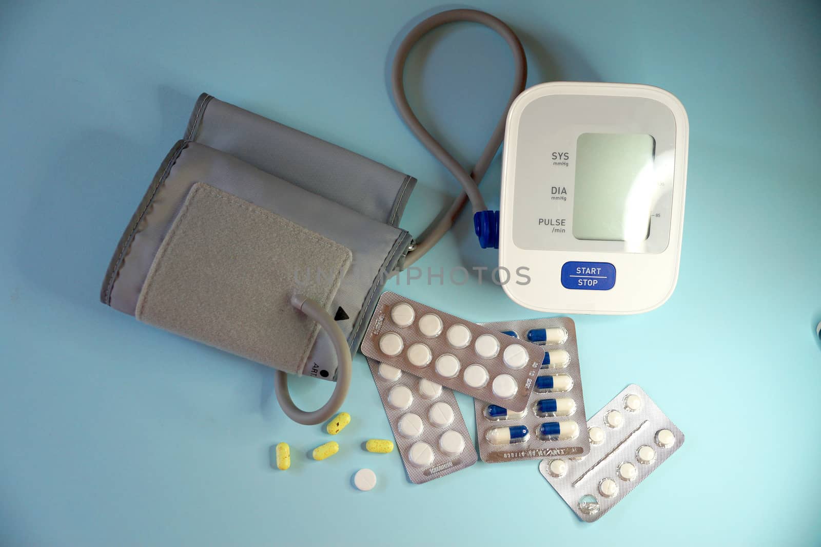 tonometer and pills on blue background, view from above