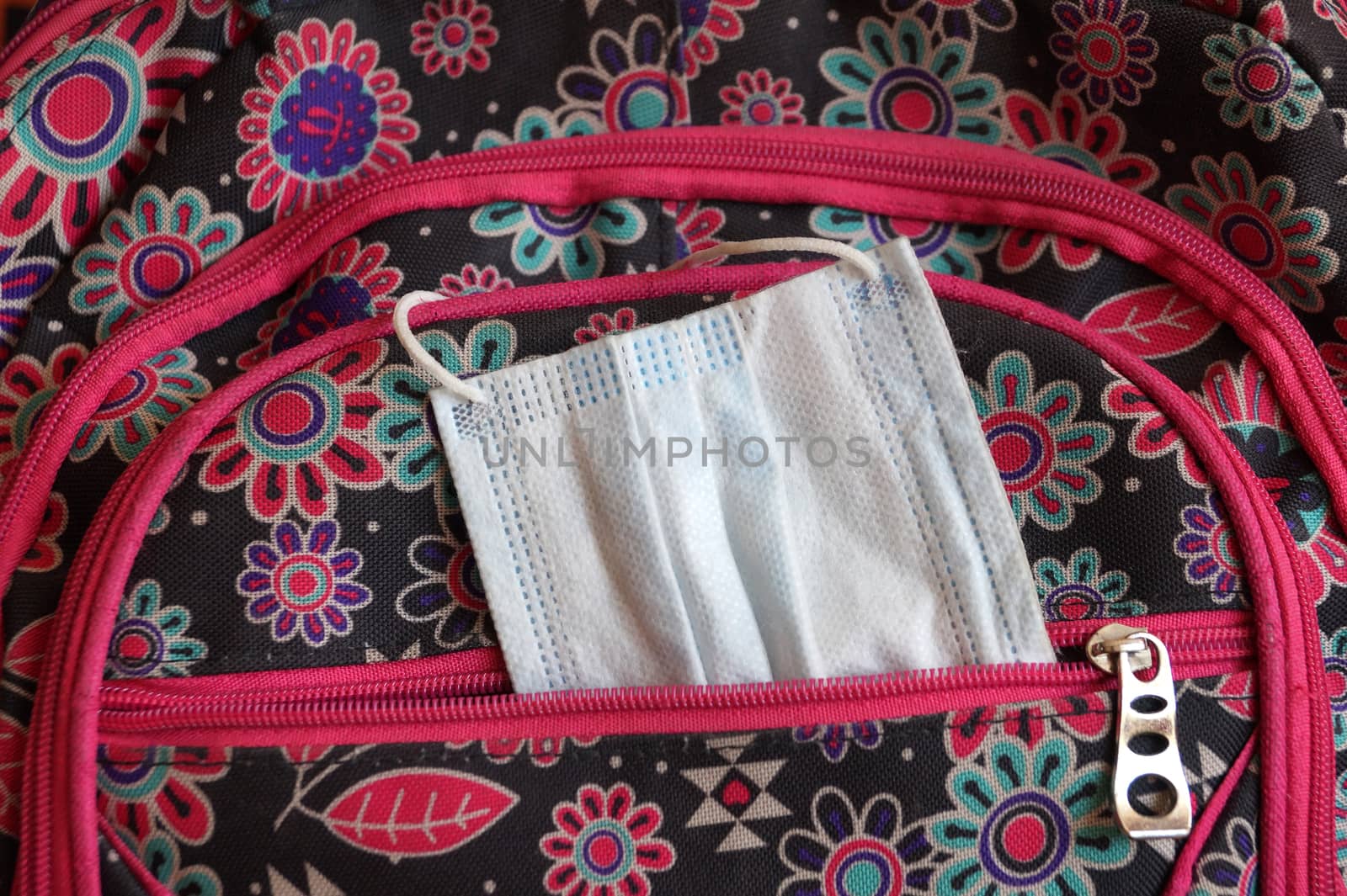 a medical mask sticking out of a school backpack close up