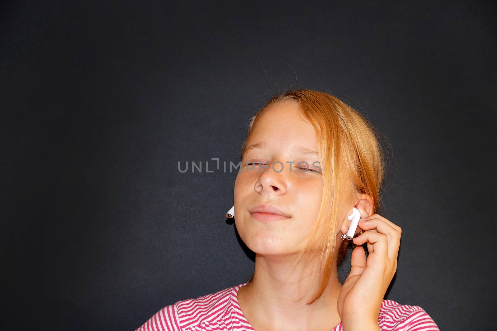 teenage girl listening to music on headphones and smiling by Annado