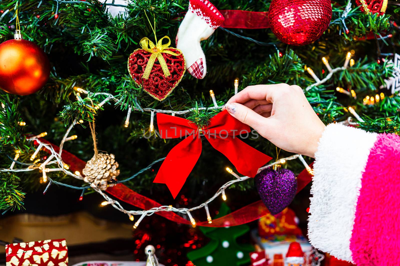 Decorating Christmas tree, hand putting Christmas decorations on fir branches. Christmas hanging decorations.