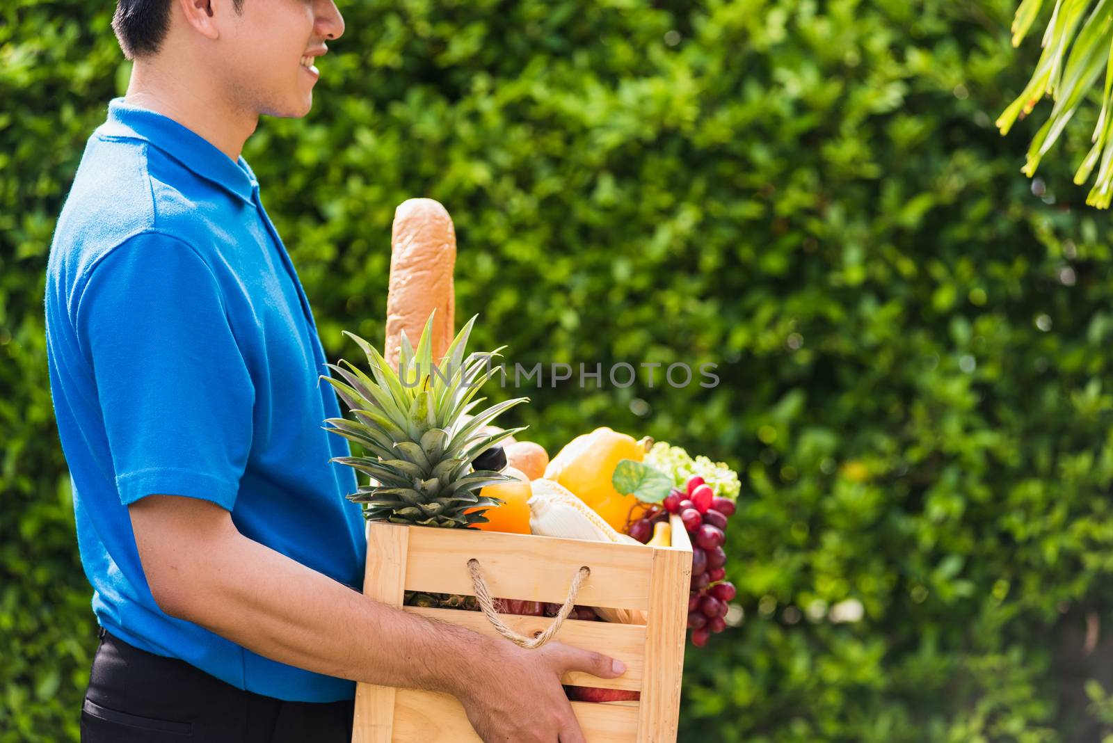 Man farmer wears delivery uniform he holding full fresh vegetabl by Sorapop