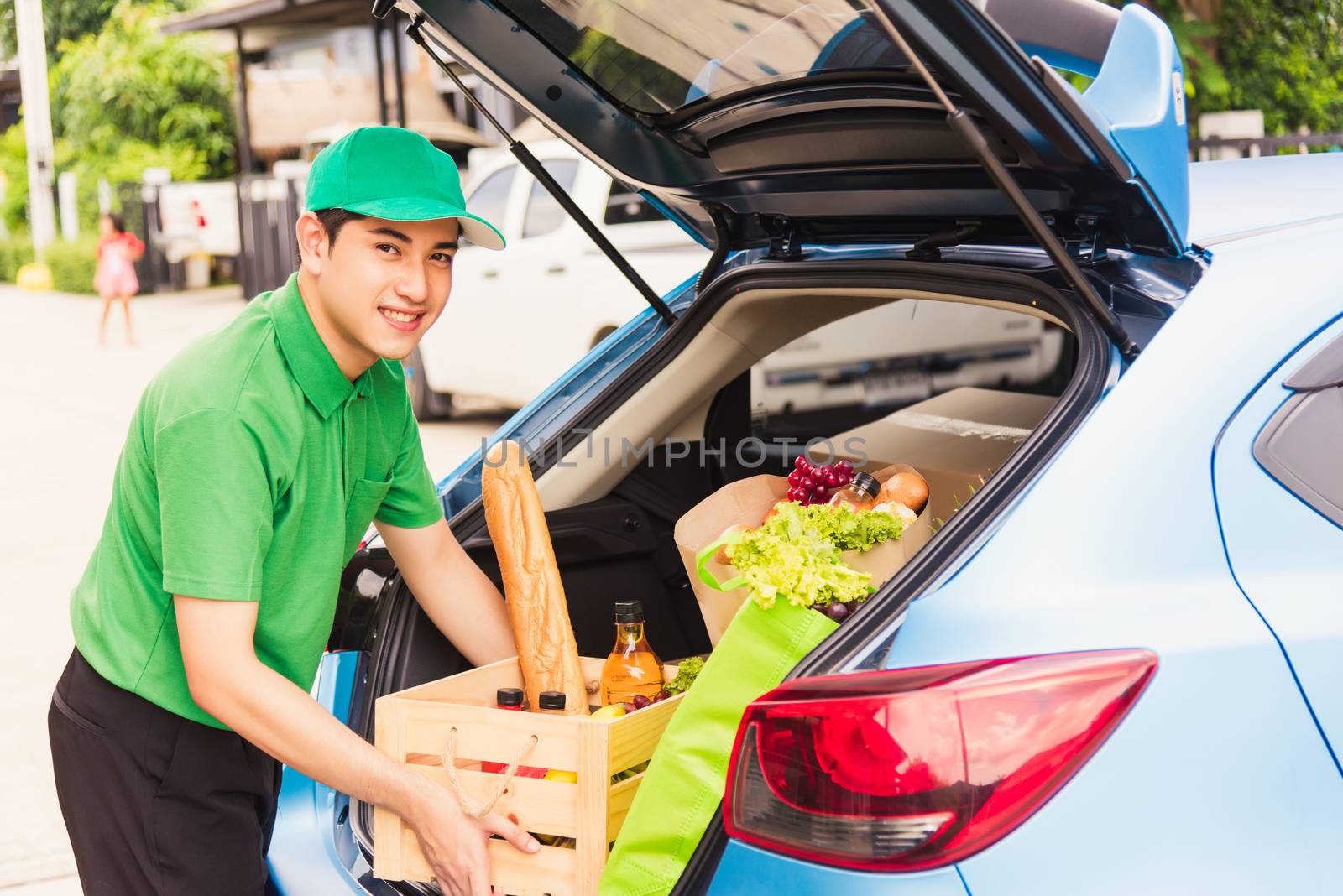 Asian delivery man grocery prepare service giving fresh vegetables food and fruit full in wooden basket on back car to send woman customer at door home after pandemic coronavirus, Back to new normal