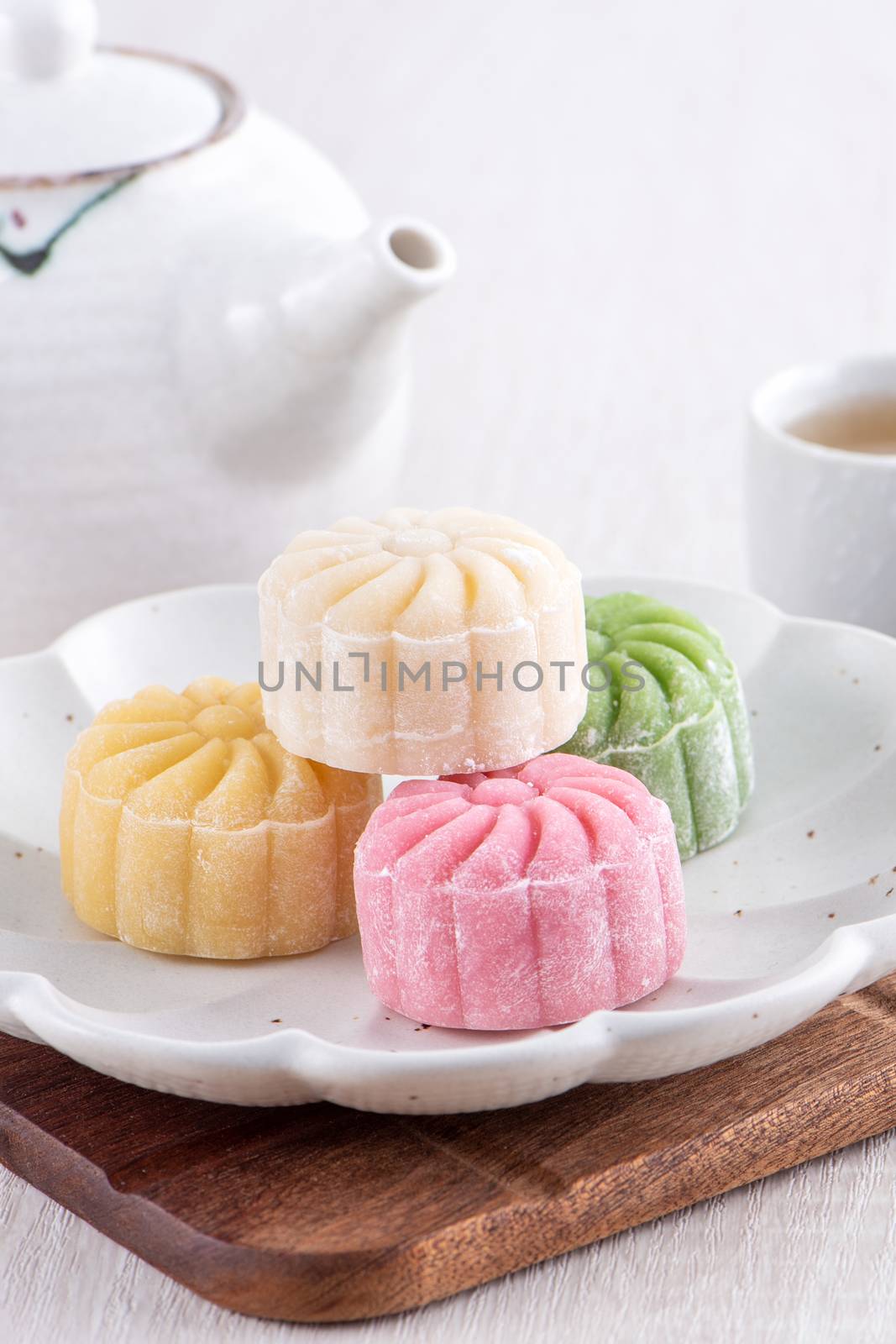 Colorful snow skin moon cake, sweet snowy mooncake, traditional savory dessert for Mid-Autumn Festival on bright wooden background, close up, lifestyle.