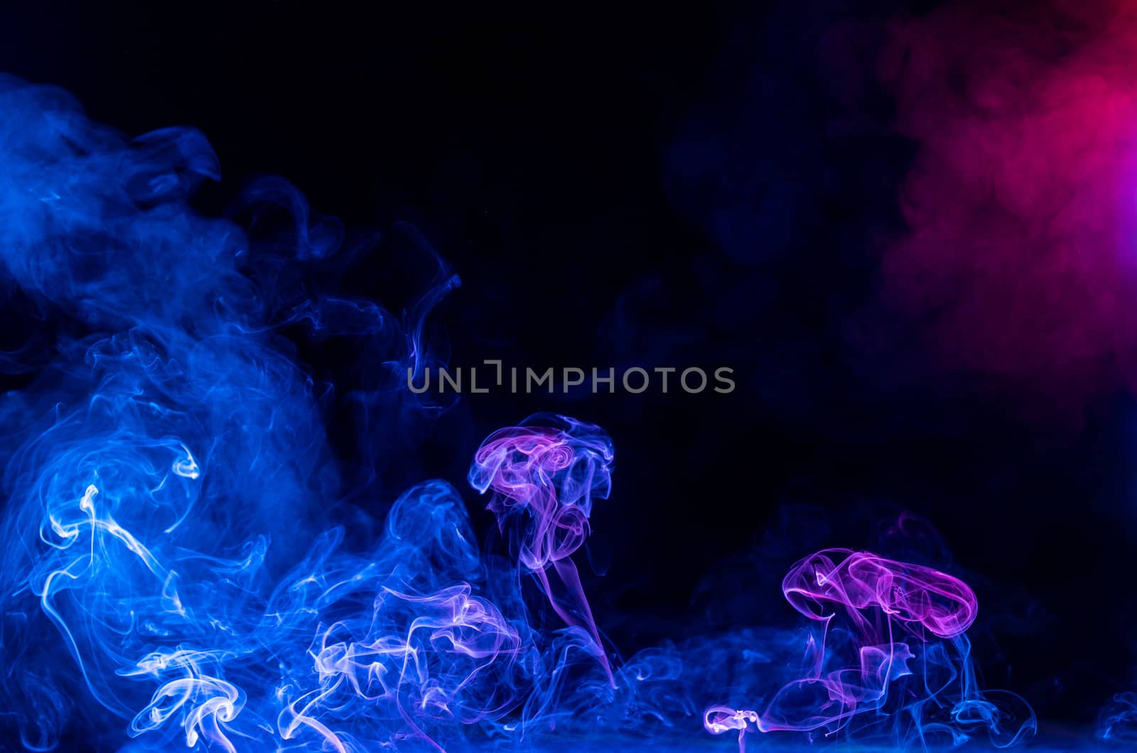 Conceptual image of multi-colored smoke isolated on dark black background, Halloween design element.