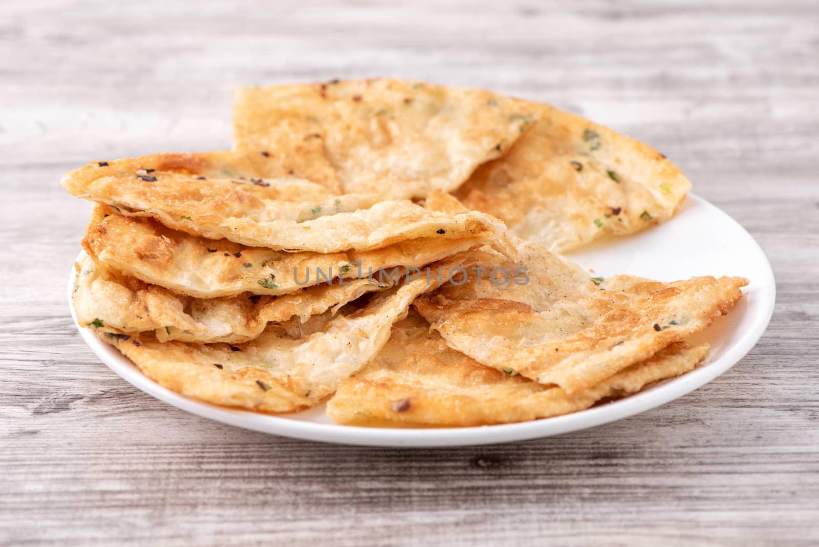 Taiwanese food - delicious flaky scallion pie pancakes on bright wooden table background, traditional snack in Taiwan, close up.