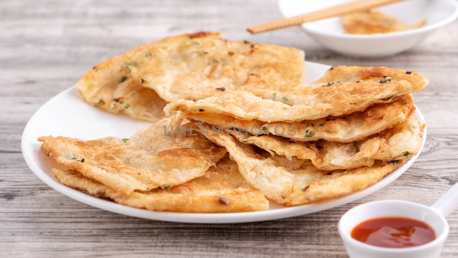 Taiwanese food - delicious flaky scallion pie pancakes on bright wooden table background, traditional snack in Taiwan, close up.