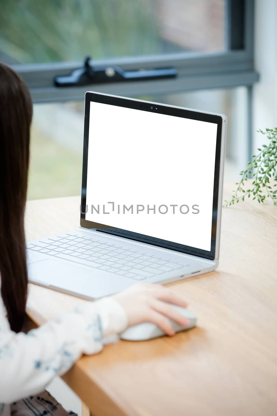 A young female child uses a computer in remote learning for her school work