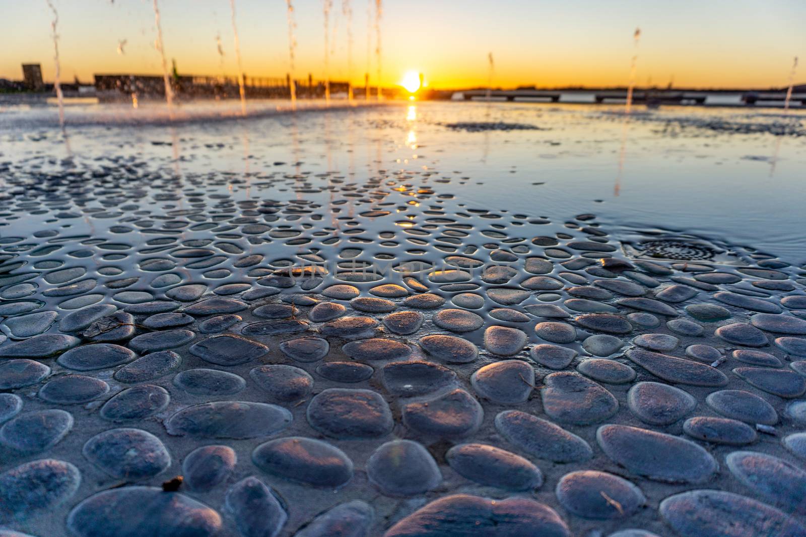 Patterned stones on base of water feature with golden sunrise background on Strand waterfront in Tauranga