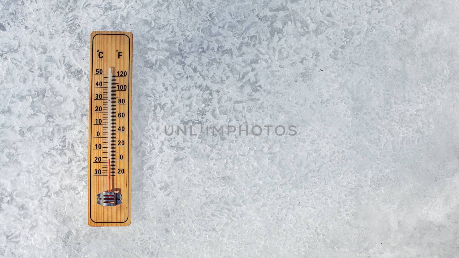 Top view on thermometer laying on layer of ice, showing temperat by Ivanko