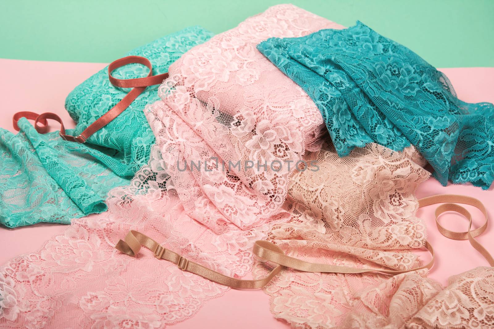pile of color rich bright lace for Lingerie, panties, and bras on pink background by polyats