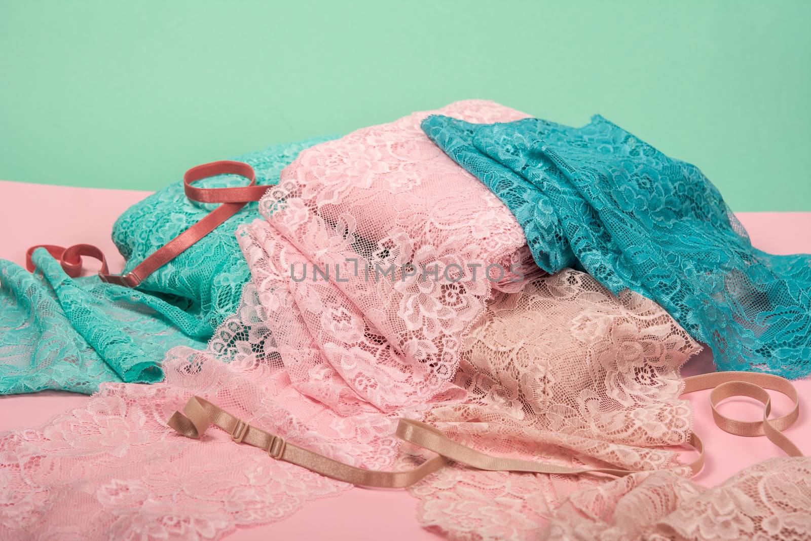 pile of color rich bright lace for Lingerie, panties, and bras on pink background by polyats