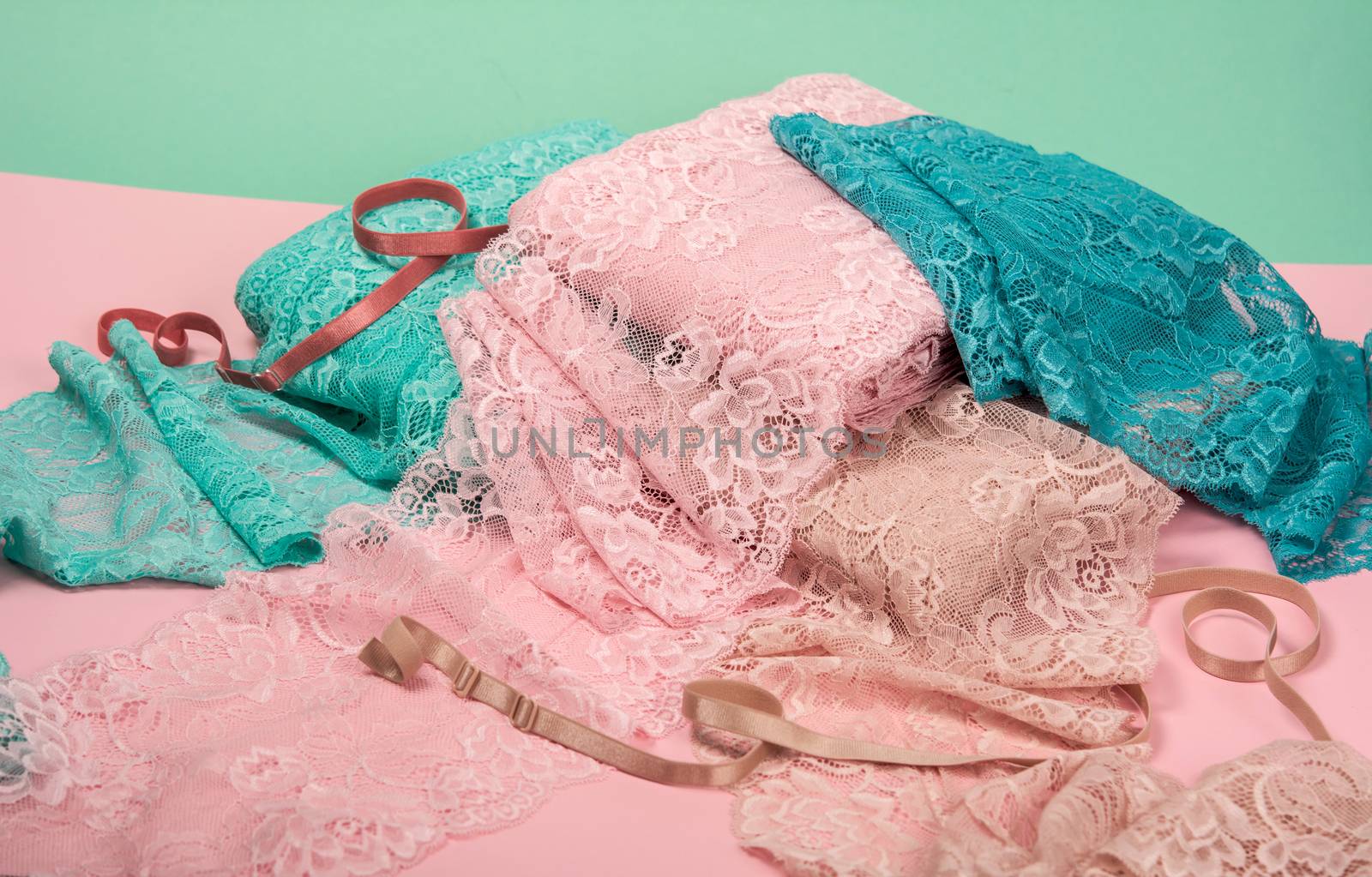 Abstract background with pile of color lace for Lingerie, panties, and bras on pink background. Delicate sophisticated glamorous elastic material. Using for Atelier and fabric store.