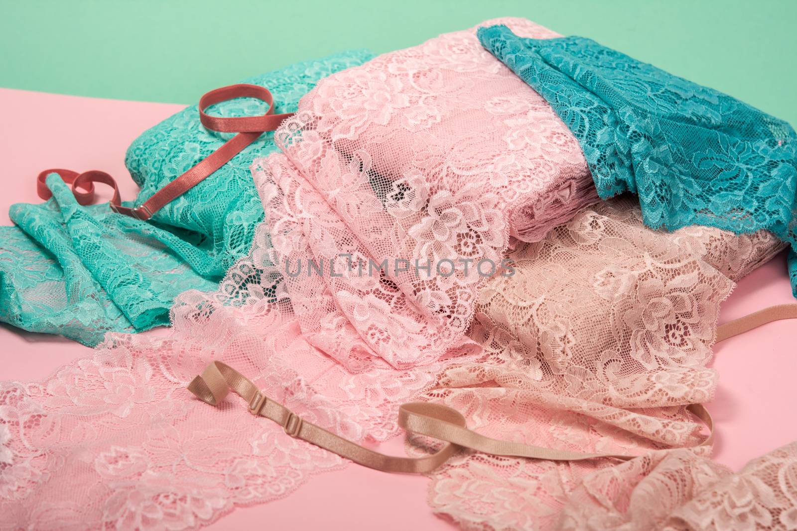 Abstract background with pile of color lace for Lingerie, panties, and bras on pink background. Delicate sophisticated glamorous elastic material. Using for Atelier and fabric store.