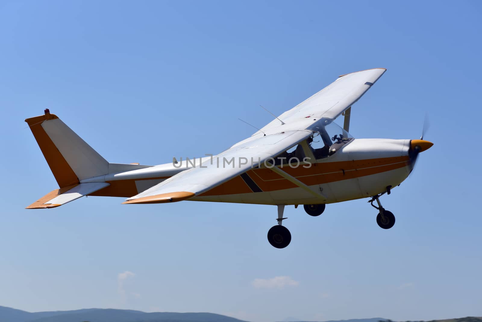 A small sports single-engine plane is flying by aselsa