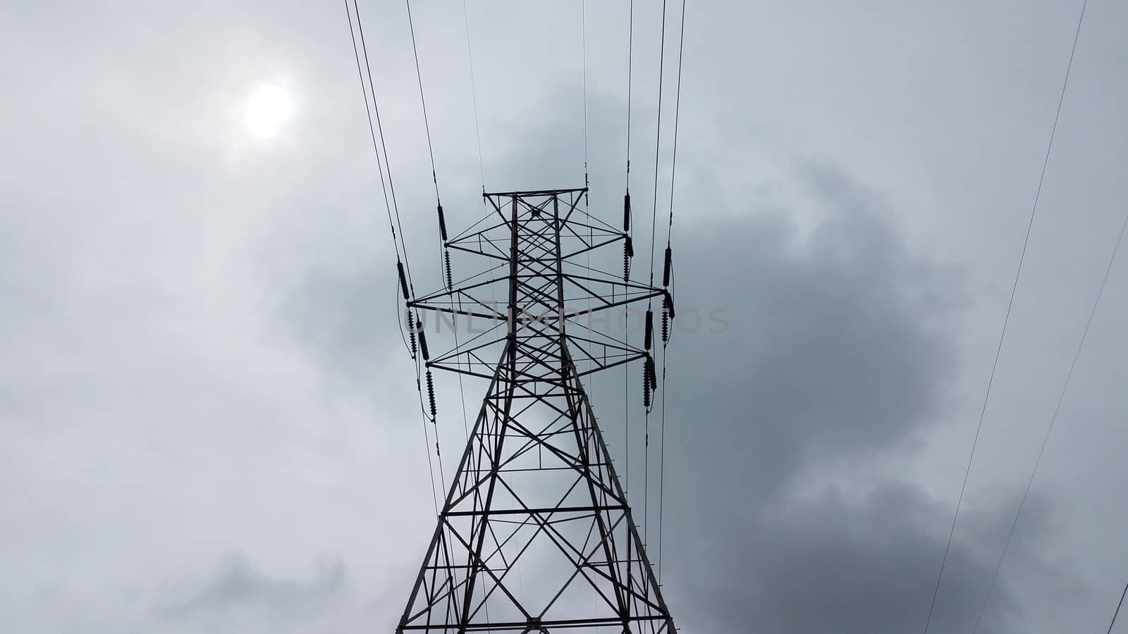 metal tower structure with power or electrical lines and clouds
