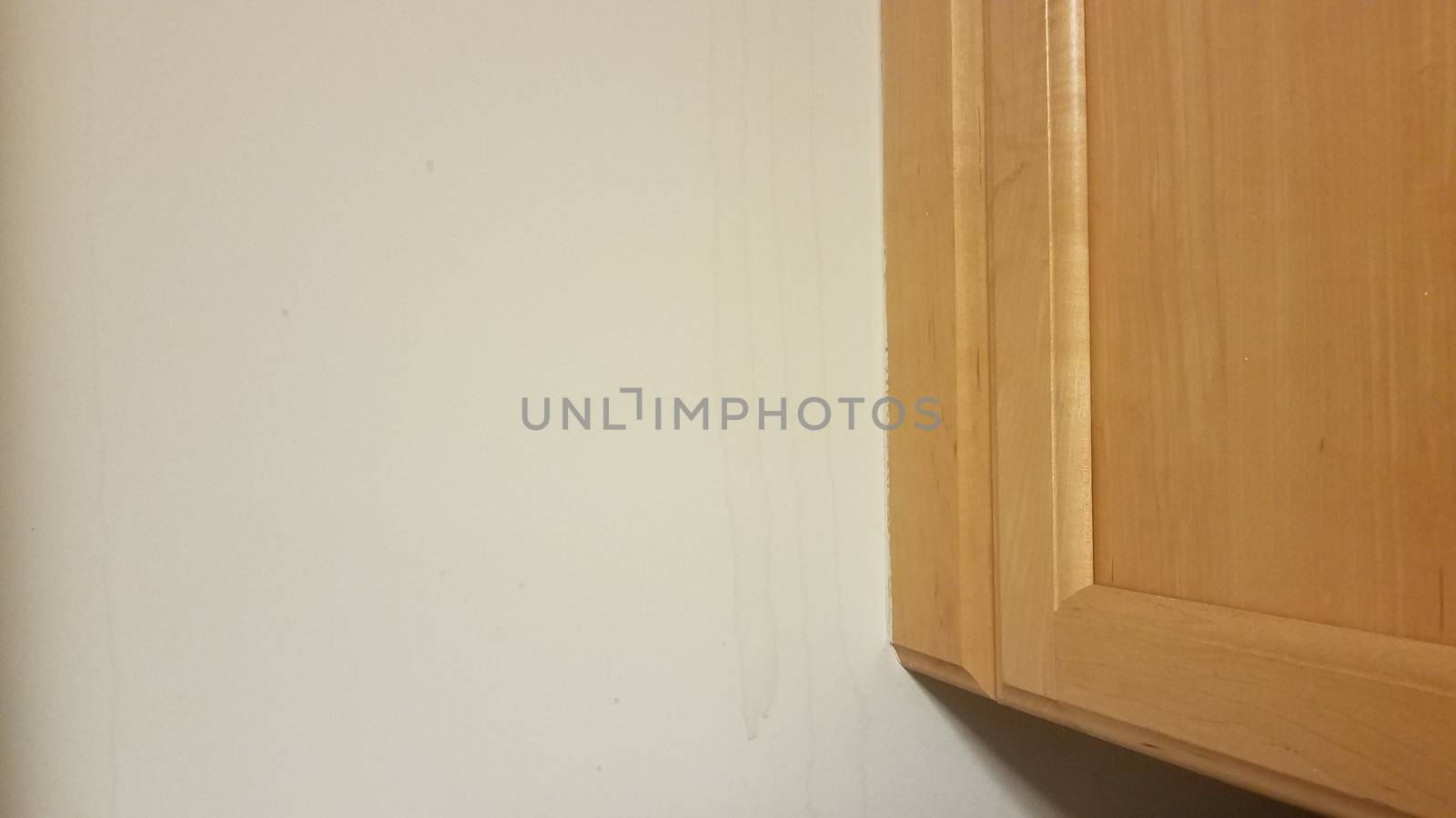 wood kitchen cabinet with water damage on drywall wall