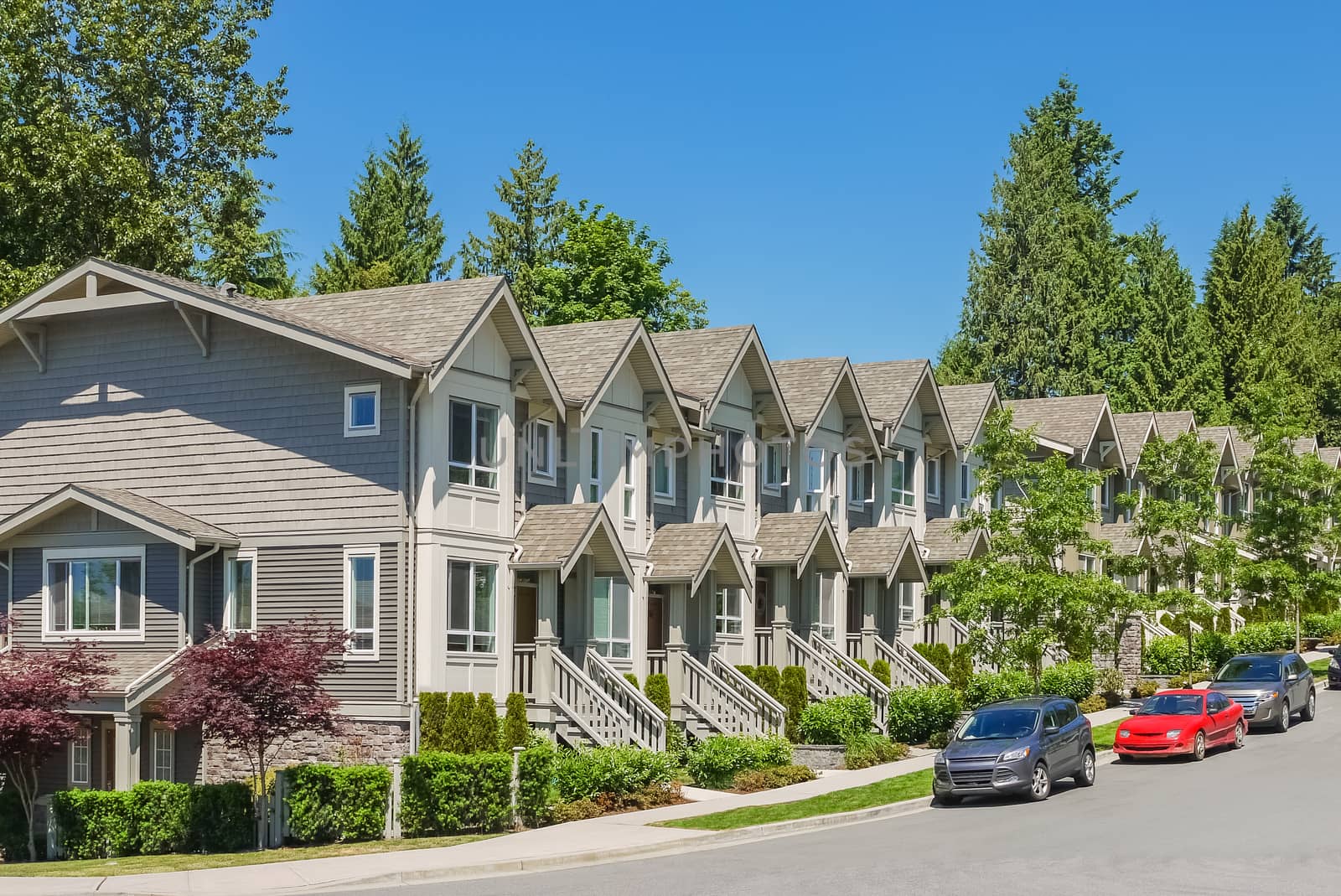 Street of new townhouses with cars parked on the road