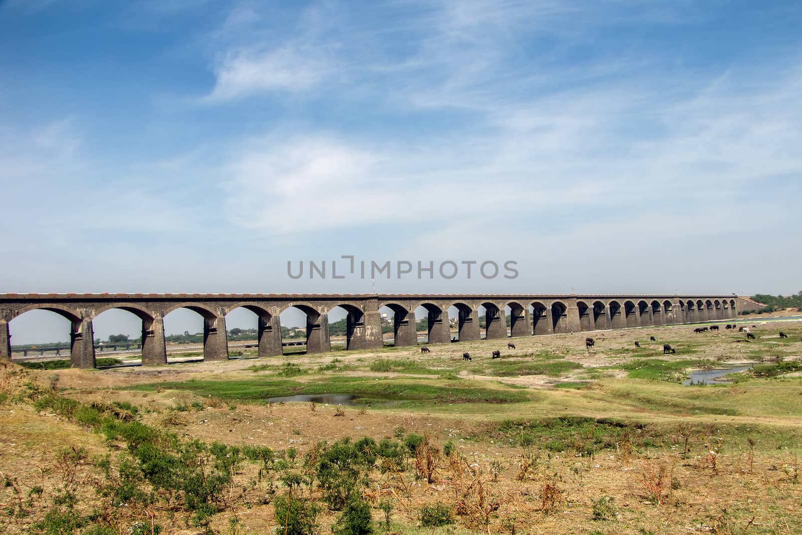 Almost dry river bed of Bheema river and an old, long stone arched railway bridge i Daund, Maharashtra, India.