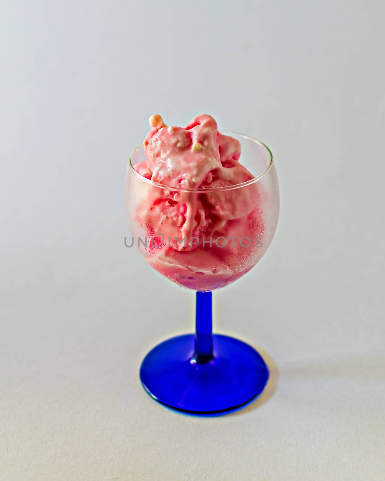 Isolated image of delicious pink strawberry ice-cream in a transparent wine glass on a clear white background.