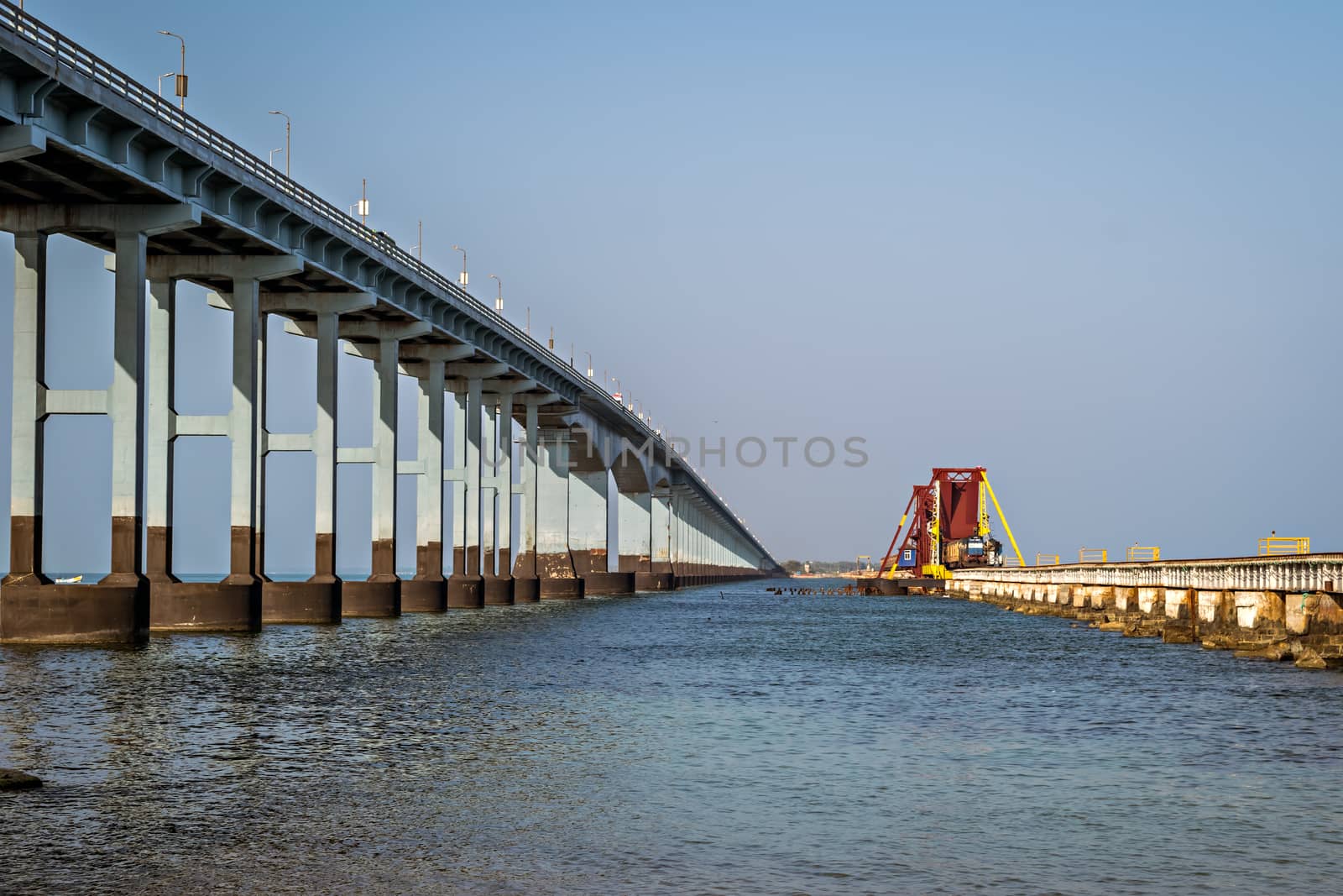 More than 100 years old India's first sea bridge for railway and a tall road bridge connecting Pamban island to mainland India. A train is passing through openable portion railway bridge.
