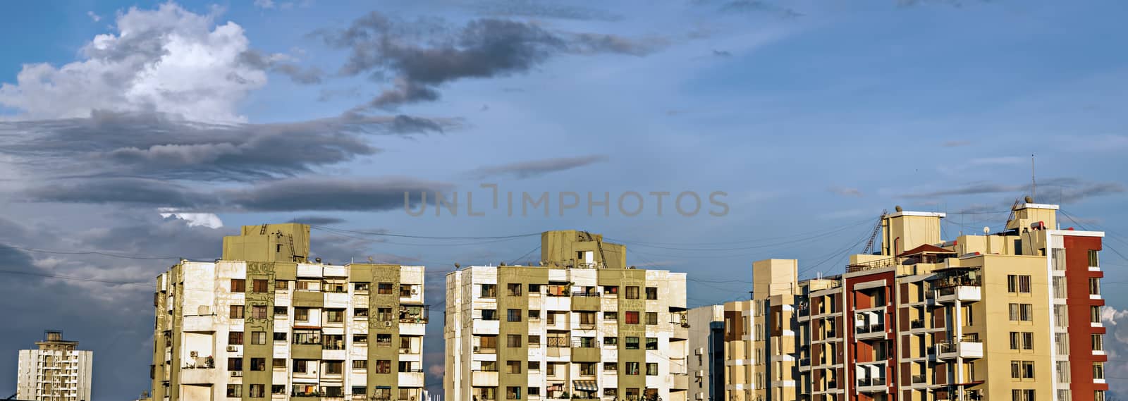 Panorama image of tall buildings in city with beautiful blue colored monsoon clouds.