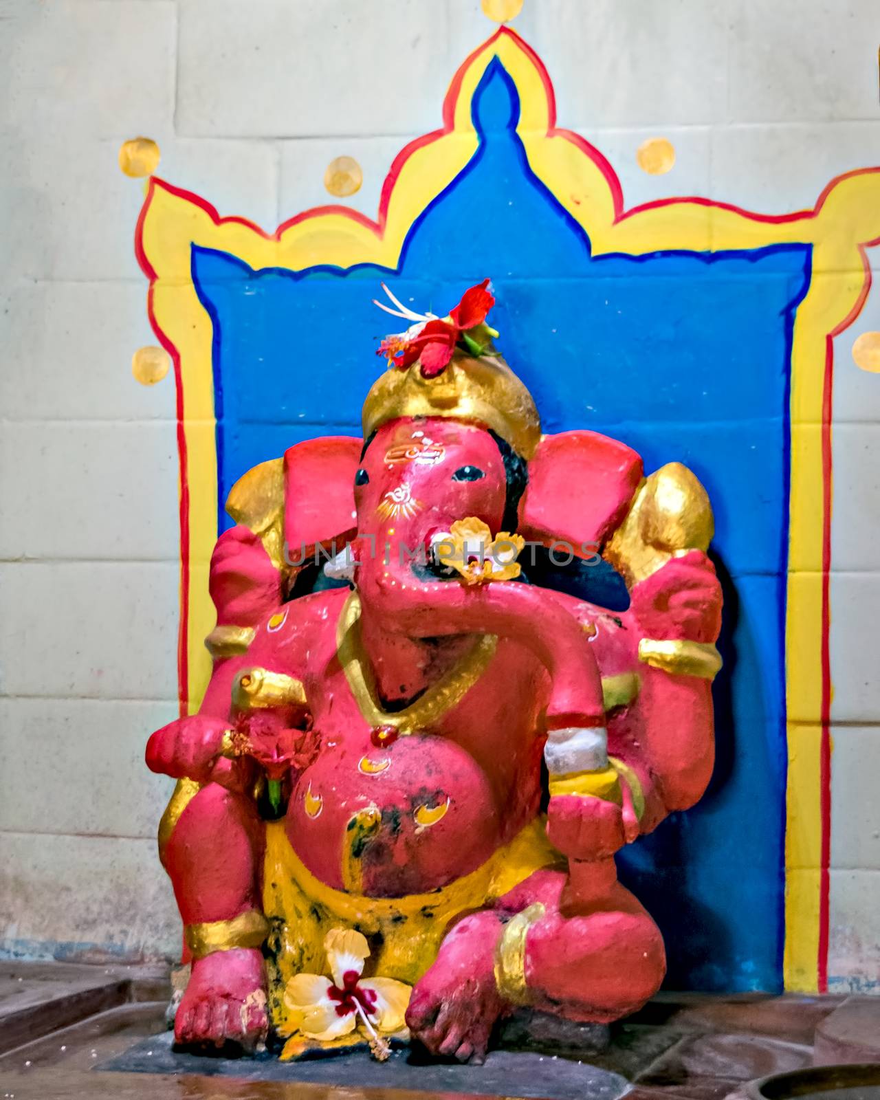 Close up image of red colored Lord ganesha idol at a temple in Velneshwar. by lalam