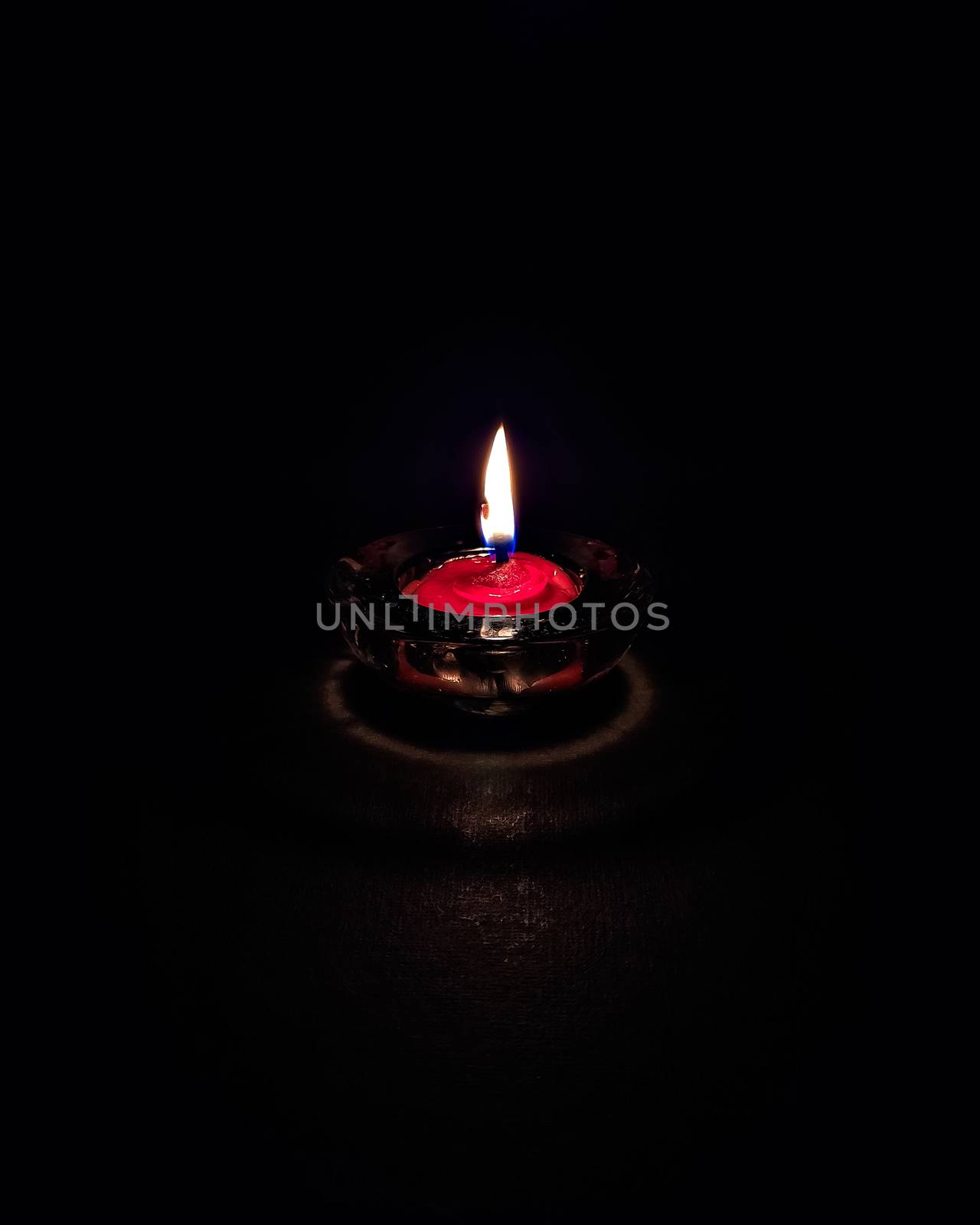 Isolated ,closeup image of small red colored wax lamp(Diya) burning in dark. by lalam