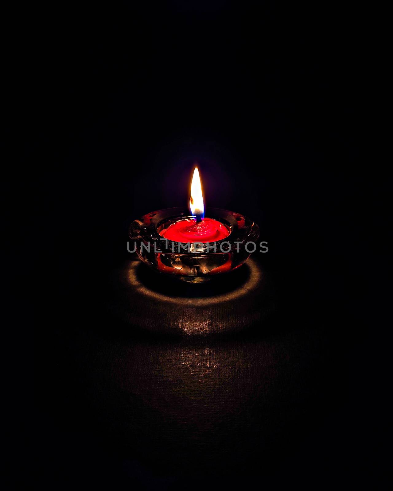 Isolated ,closeup image of small red colored wax lamp(Diya) burning in dark. by lalam