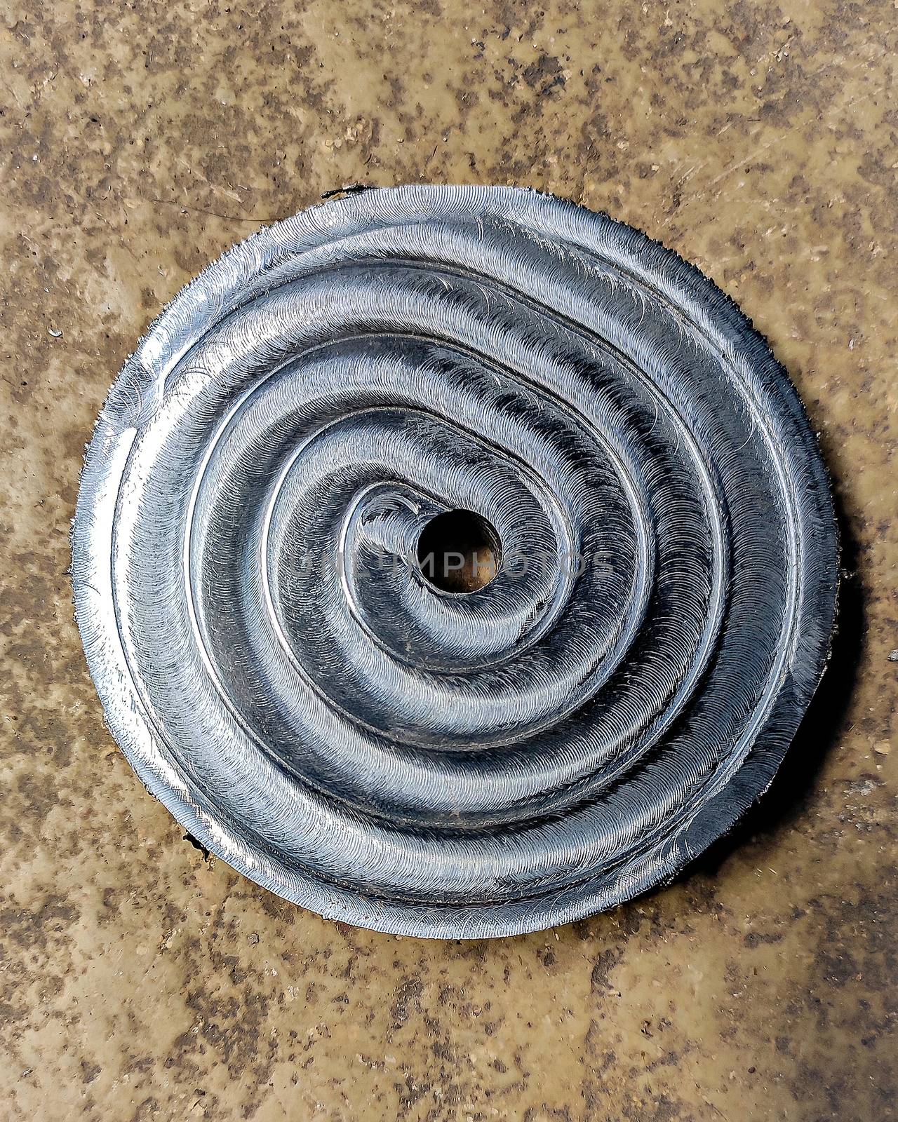 Selective focus, shallow depth of field image of Steel plate with nice spiral circular pattern formed as a result of CNC machining.