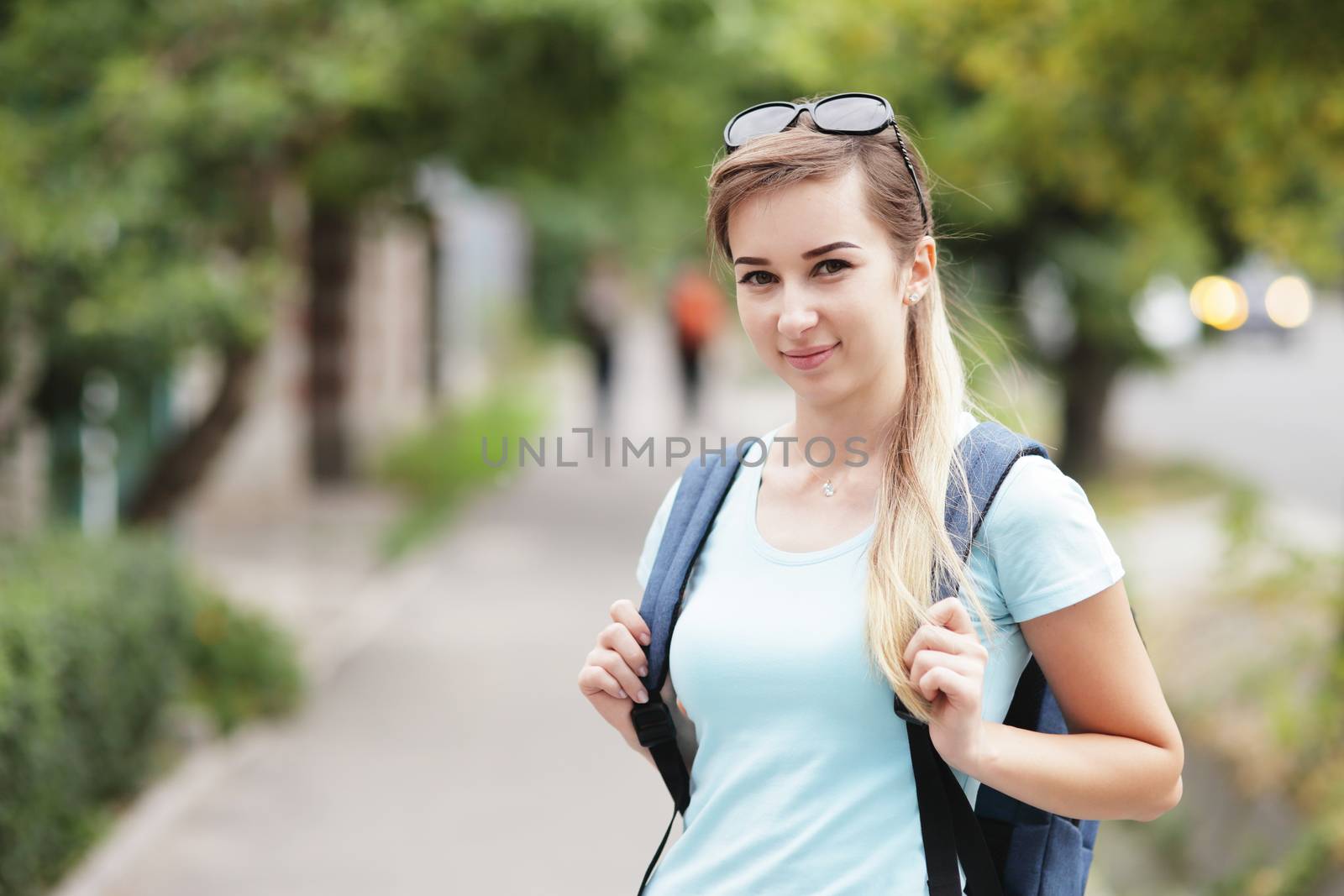 Fashion portrait of young stylish woman walking down the street, in trendy outfit, traveling with a backpack. High quality photo