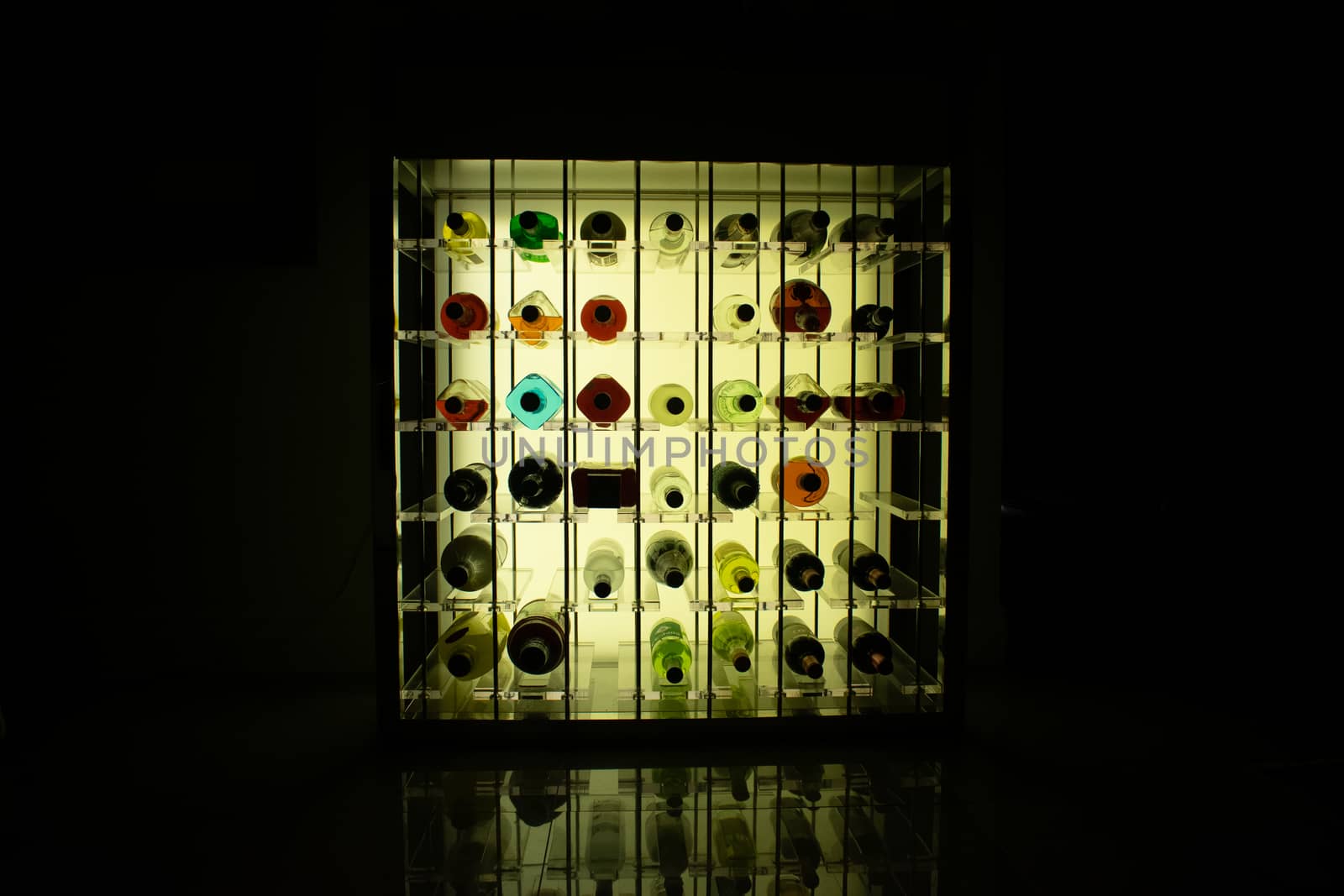 A Yellow Backlit Rack of Bottles of Wine