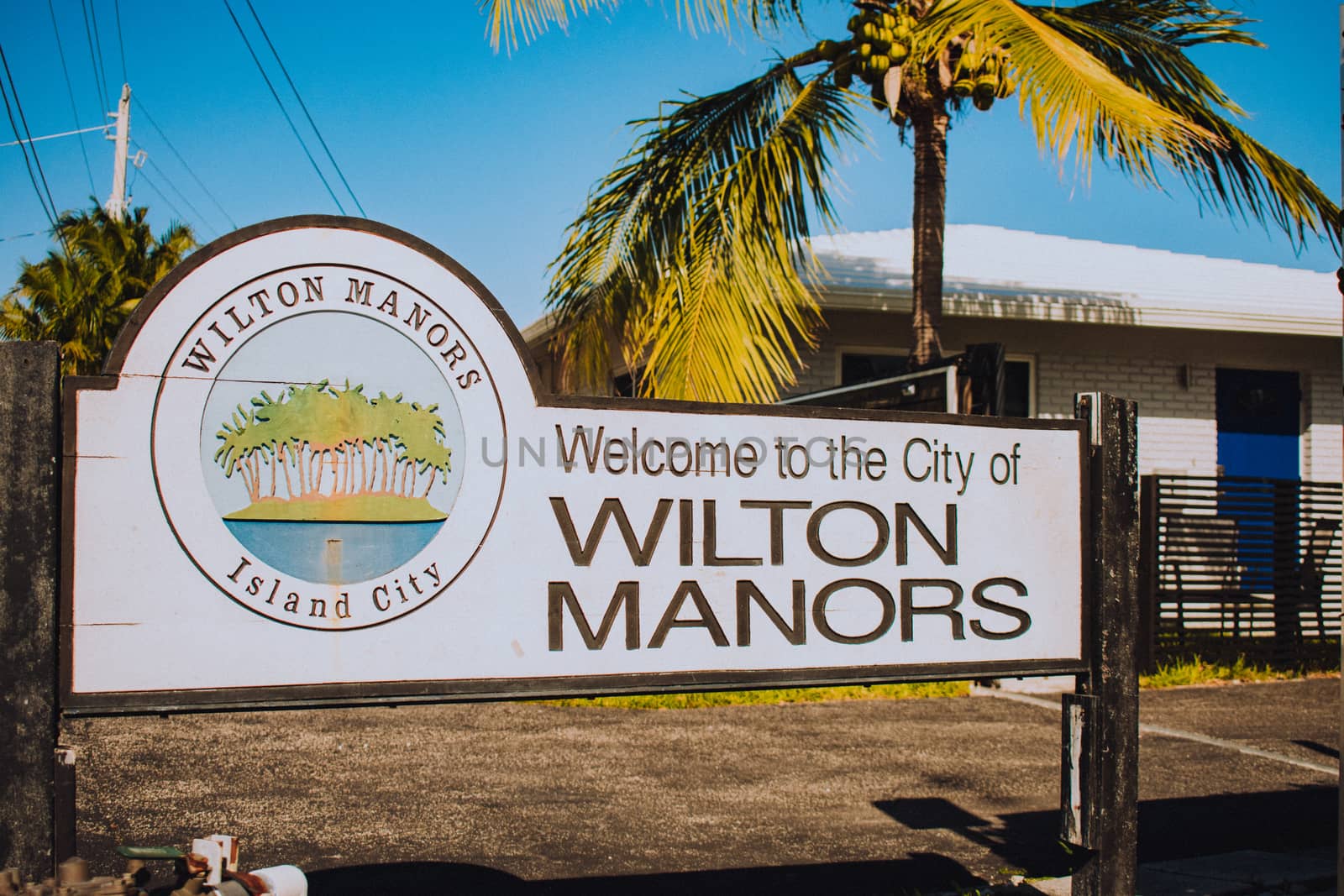 WILTON MANORS, FLORIDA - JAN 5, 2020: Sign That Says Welcome to the city of Wilton Manors With Palm Trees on an Island Graphic That Says Island City Underneath in this urban city with a population of 12,797 in 2018 