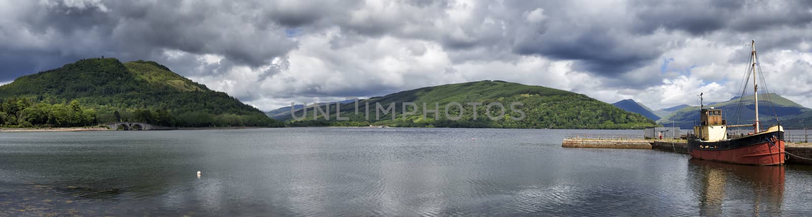 Panoramic view from Inveraray of Loch Fyne with boat moored in harbour and hills in background