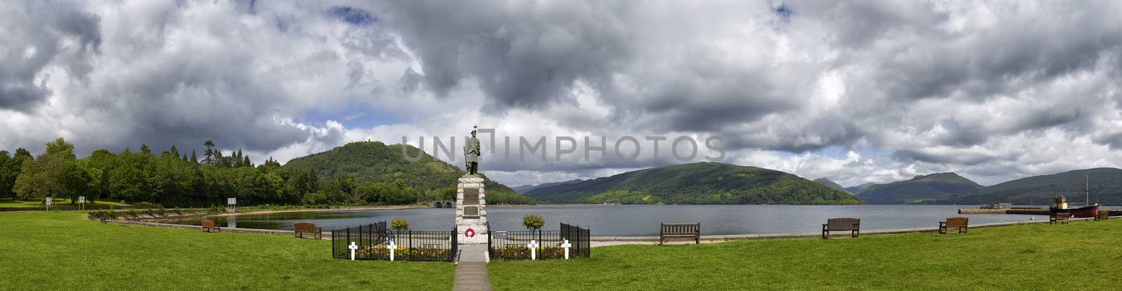 Panoramic view from Inveraray of Loch Fyne and war memorial with boat moored in harbour and hills in background