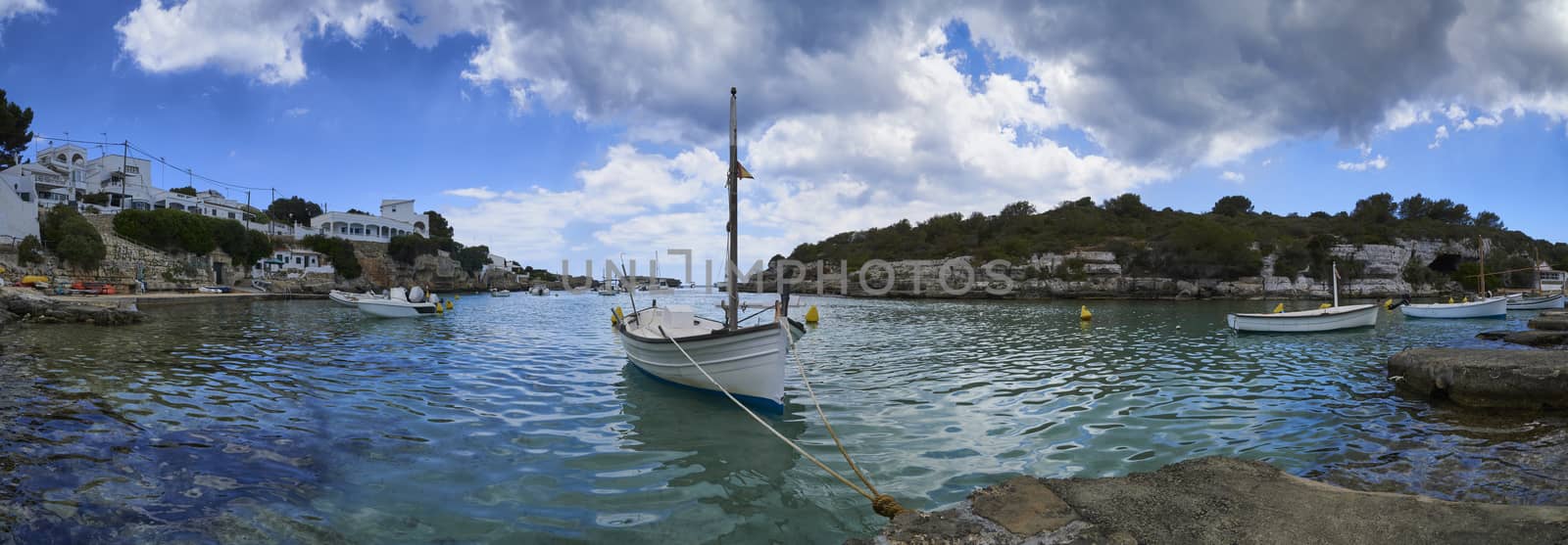 Panorama of small boats moored in the Mediterranean cove of Cala Alcaufar,Menorca,