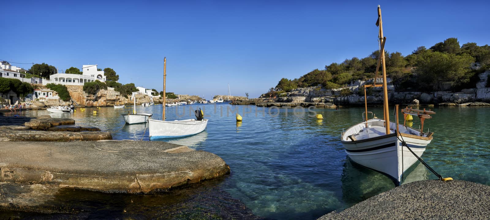 Panorama of small boats moored in the Mediterranean cove of Cala Alcaufar,Menorca,