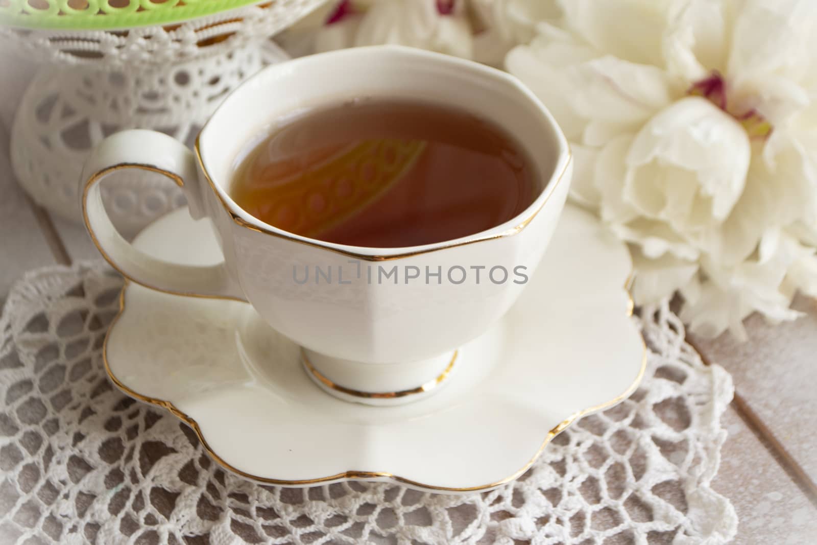 Tea on a summer day. Still life with a cup of tea, white bouquet of peonies on a white lace tablecloth