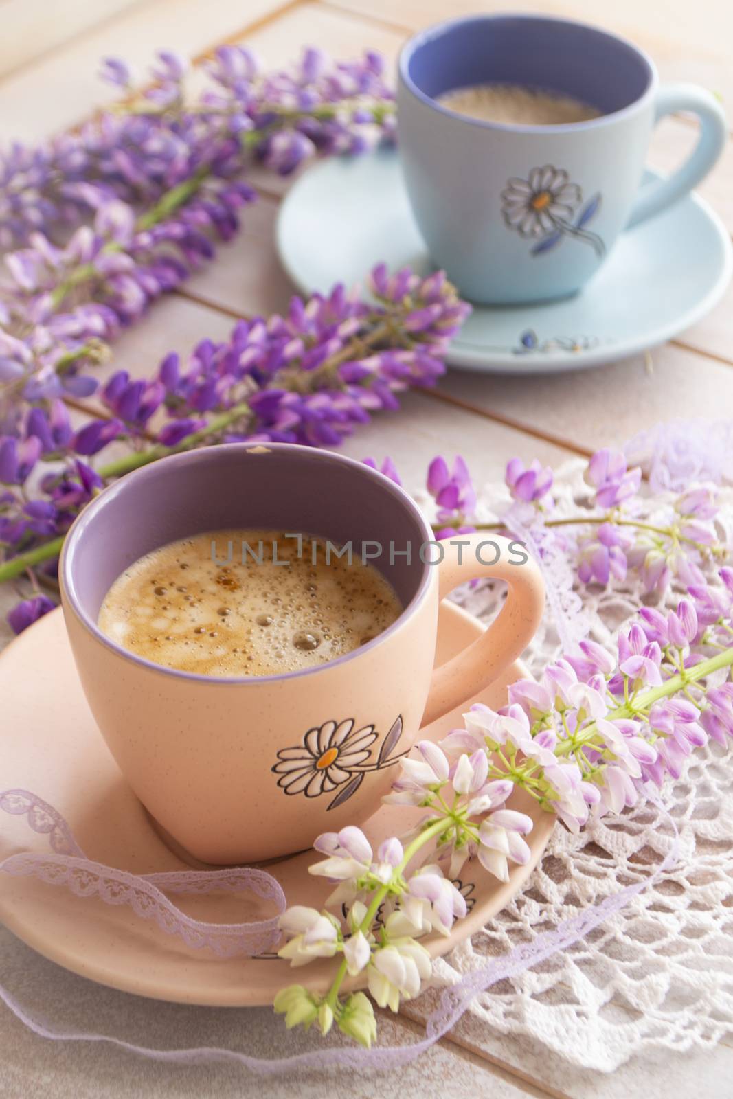 cup of coffee and lupine flowers on a white wooden table. Vertical image