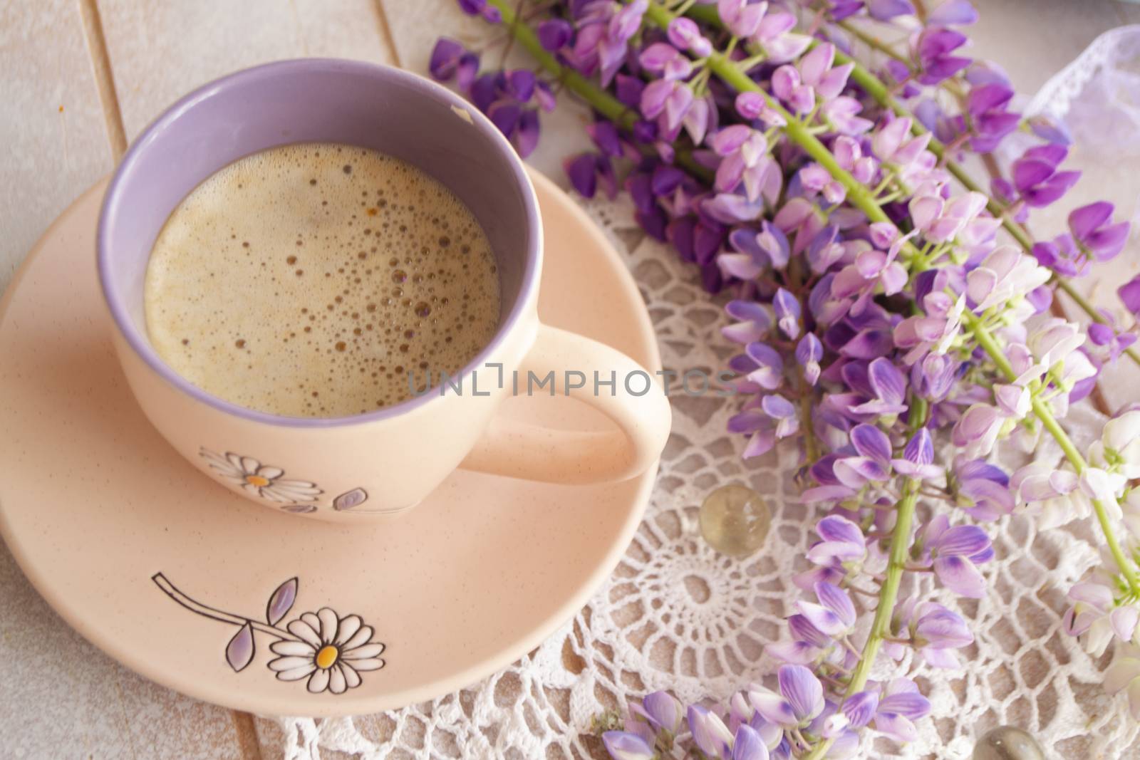 Morning scene with a cup of coffee surrounded by wild flowers of lupine