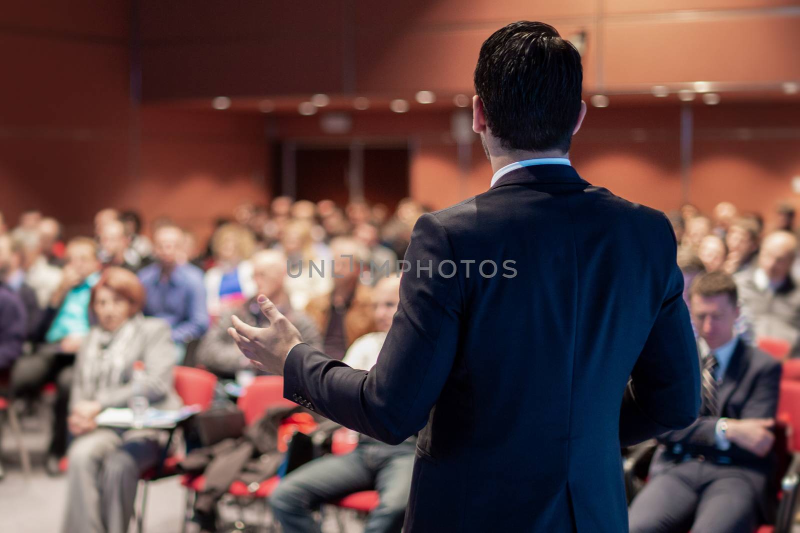 Speaker giving a talk on corporate business conference. Unrecognizable people in audience at conference hall. Business and Entrepreneurship event.