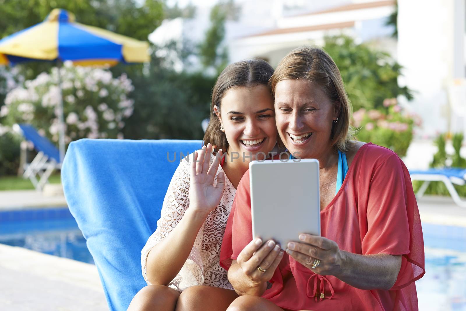 Mother and Daughter keeping in touch with friends and family using a digital tablet while on holiday