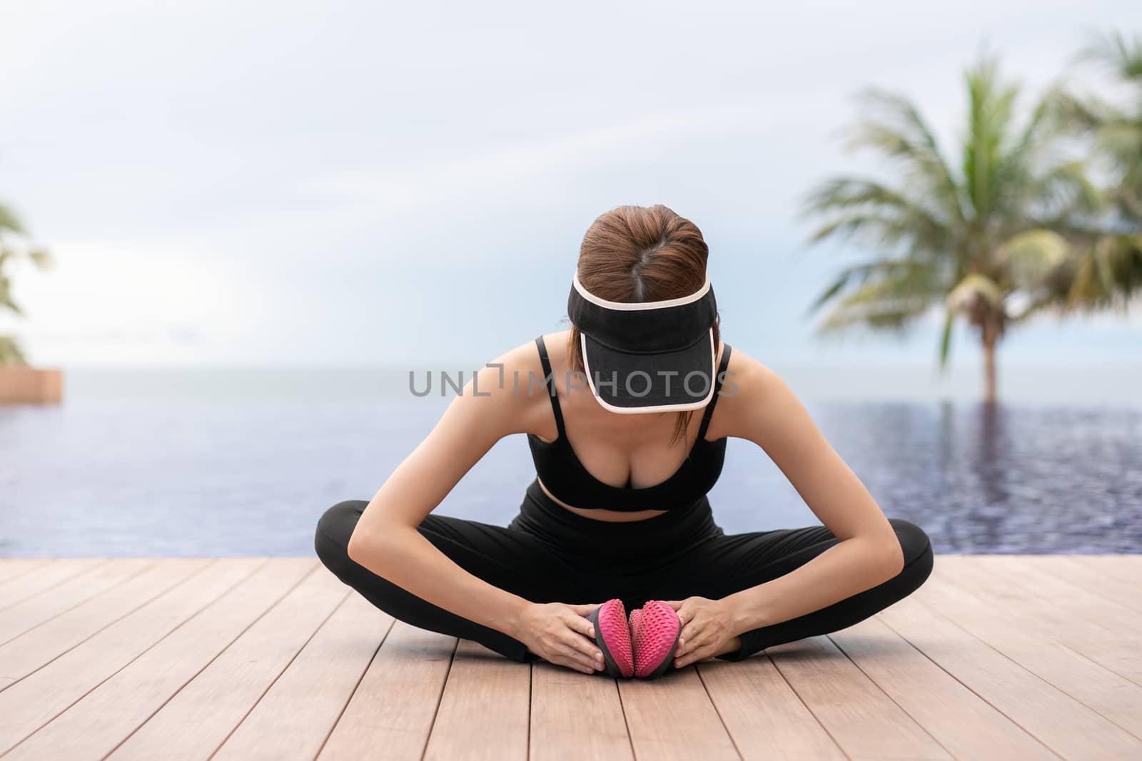 Sports woman stretching and preparing to run by the pool in the morning.