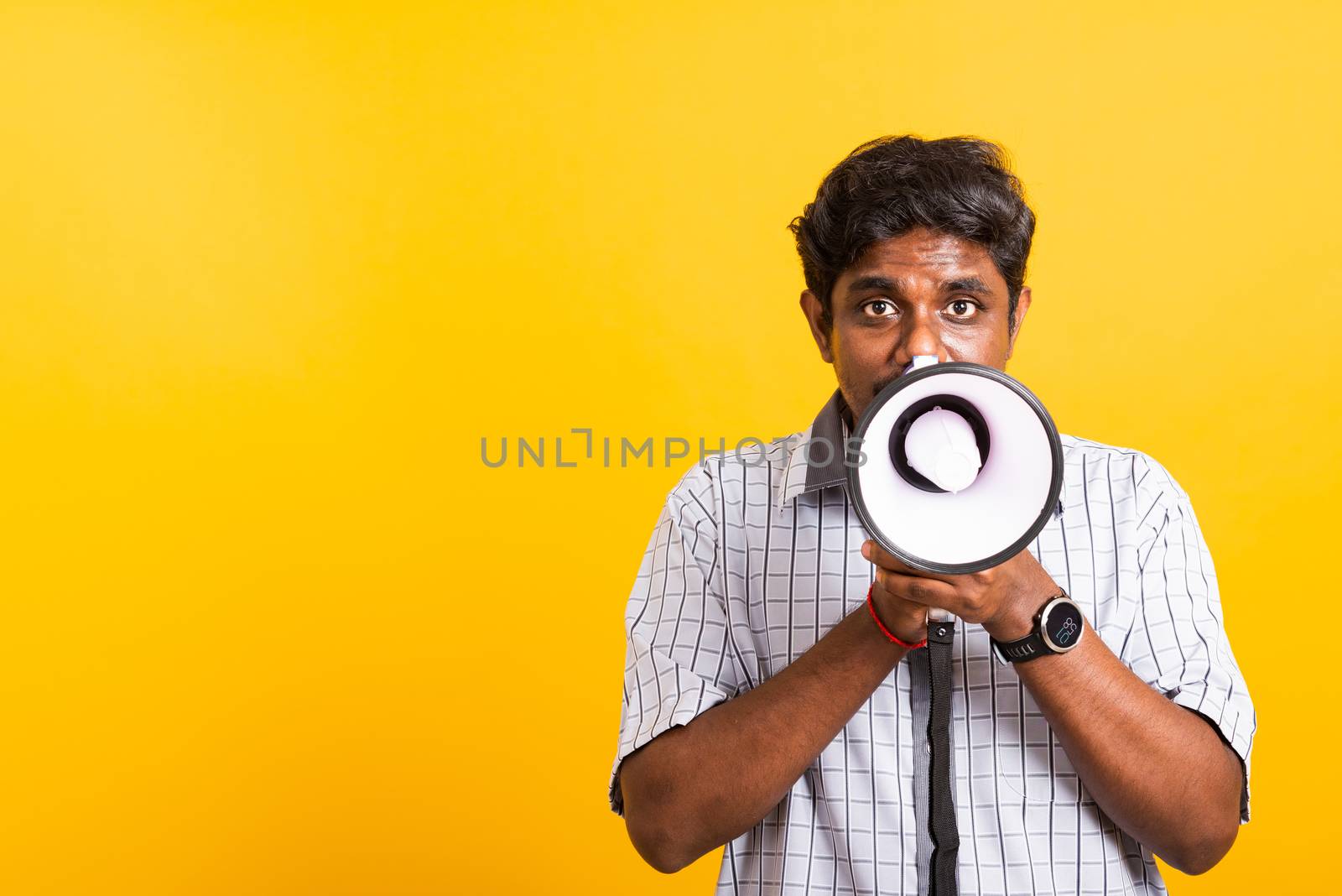 Asian happy portrait young black woman standing to make announcement message shouting screaming in megaphone, studio shot isolated on yellow background with copy space