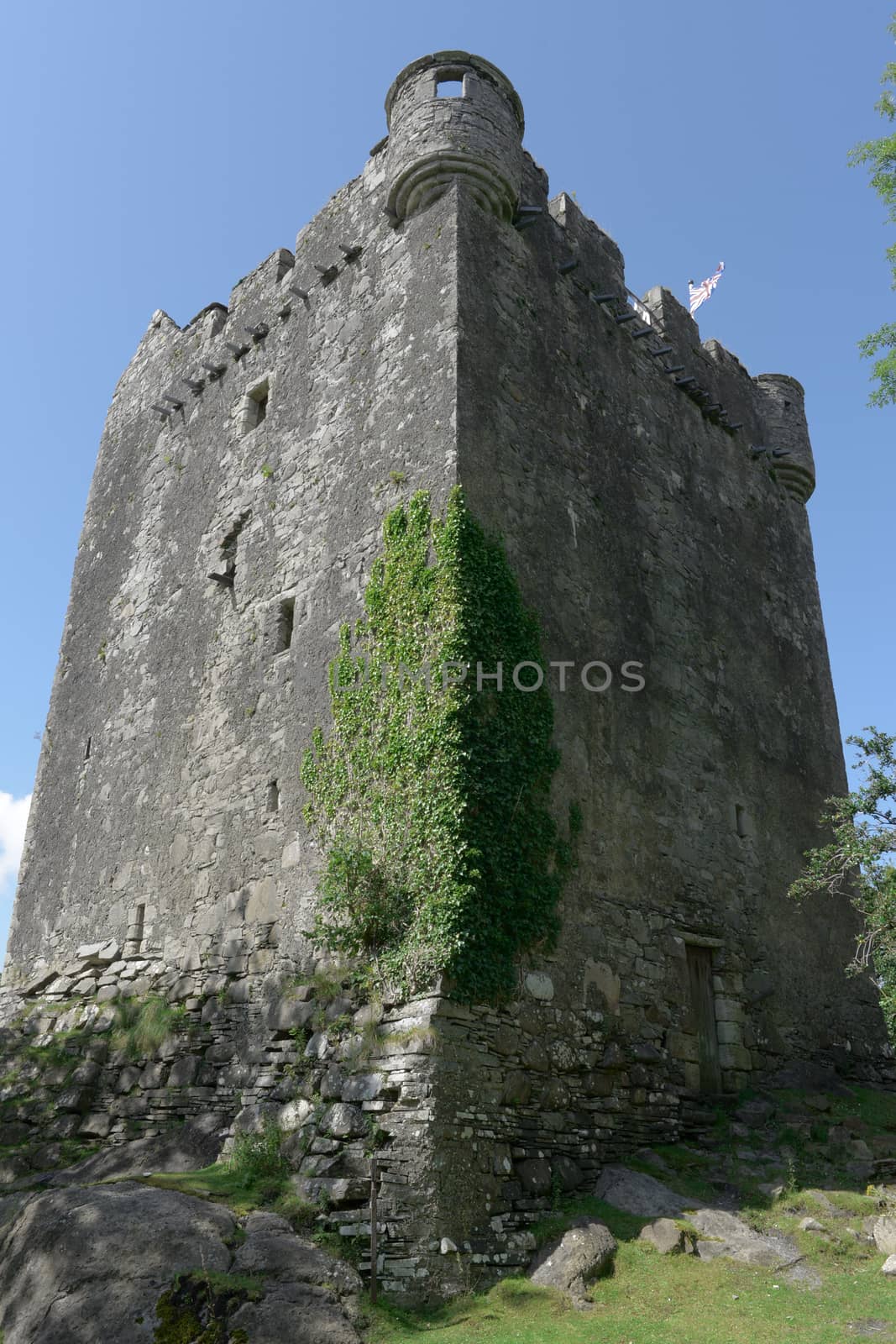 Sun and shade contrast across the imposing vertical exterior walls of moy castle near lochbuie on the isle of mull. Blue skies and strong composition