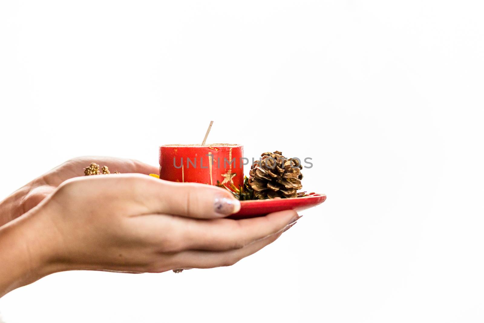 Hands holding decorated Christmas red candle isolated on white background.