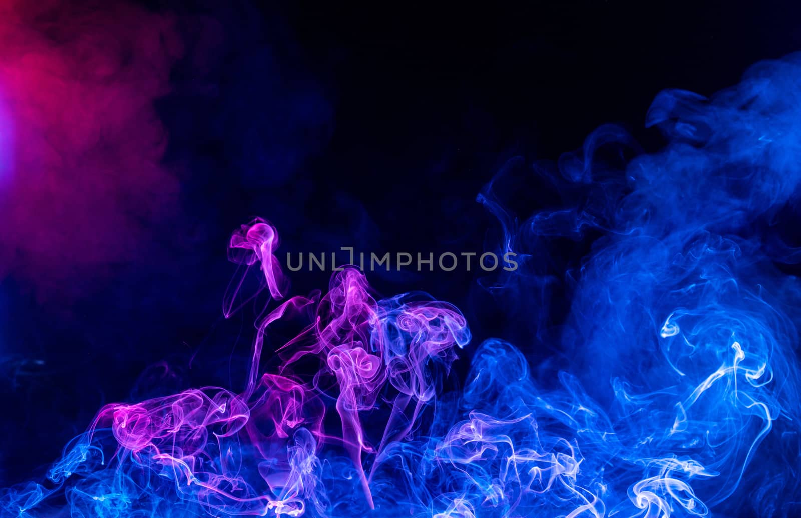 Conceptual image of multi-colored smoke isolated on dark black background, Halloween design element.