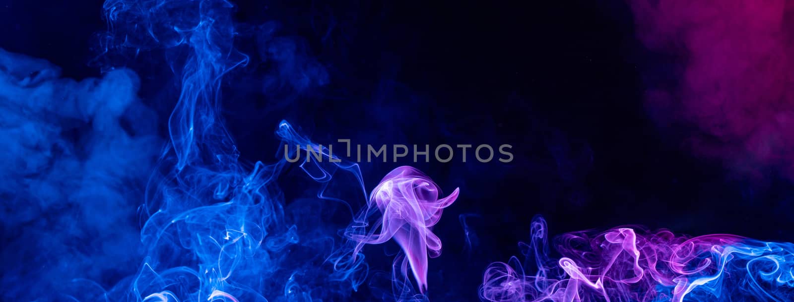 Conceptual image of multi-colored smoke isolated on dark black background, Halloween design element.