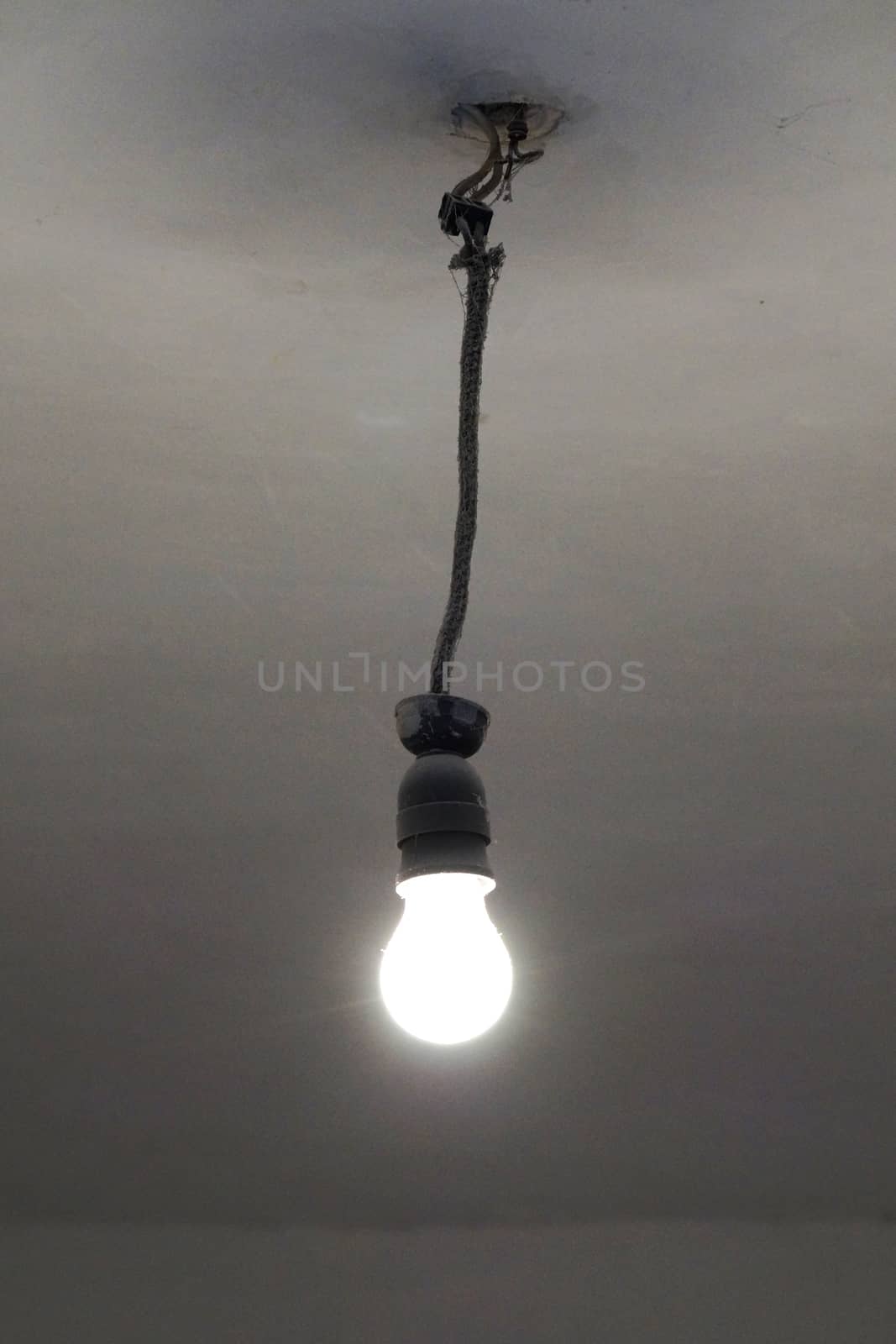 old included light bulb on the ceiling without lampshade.