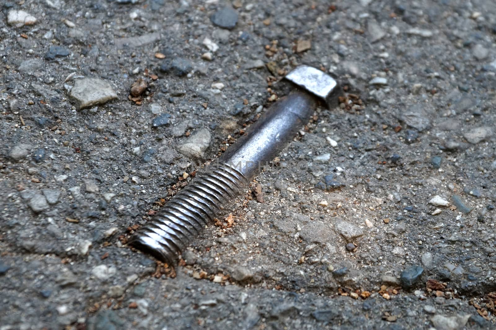 metal bolt in the asphalt on the road close up